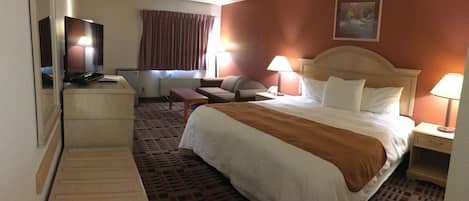 A hotel room with a bed, a desk, a television, and a window with curtains.