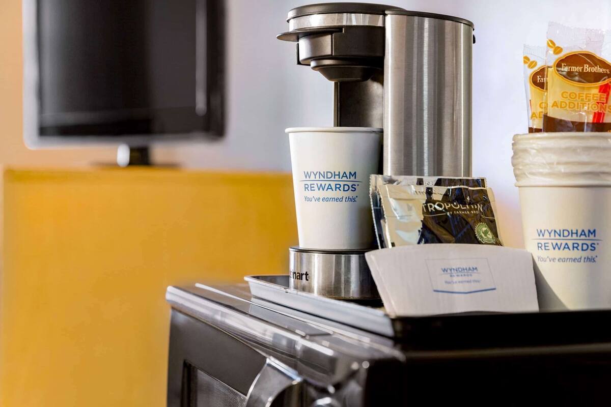 Una cafetera, cápsulas de café y una taza con la marca 'WYNDHAM REWARDS'.