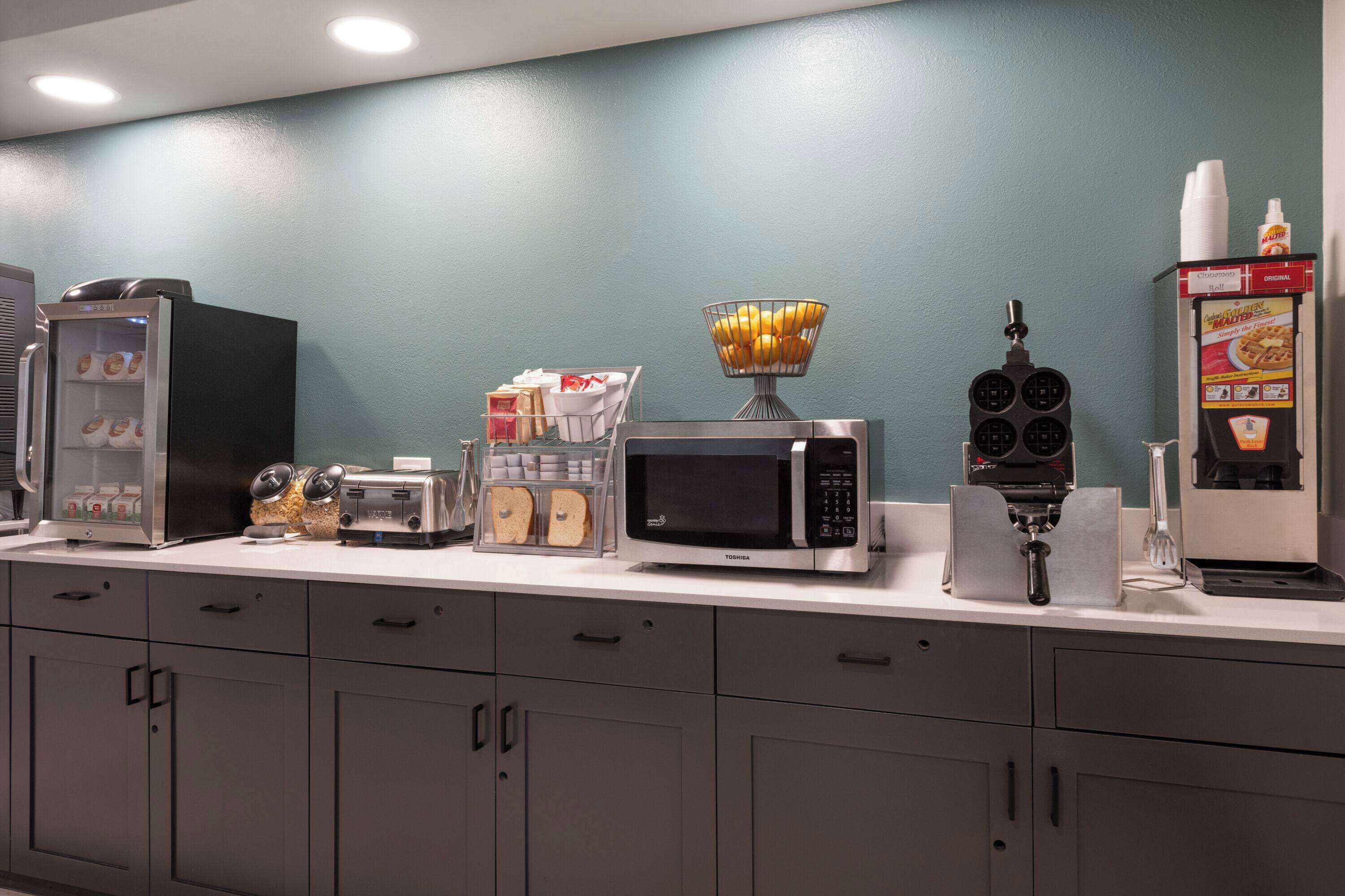 A kitchenette with a refrigerator, microwave, toaster, and coffee maker.