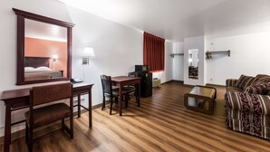 A hotel room with a wooden floor, a dining table with chairs, a sofa, a TV, and a mirror. - Super Stay Plus (Morristown)