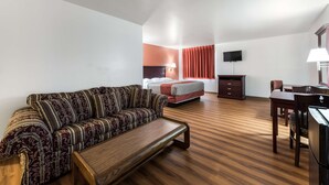 A hotel room with a sofa, a bed, a desk, and a television. - Super Stay Plus (Morristown)
