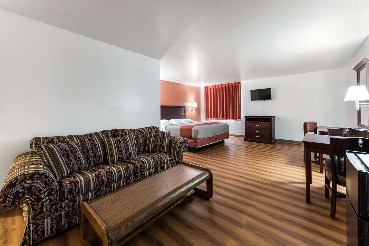 A hotel room with a sofa, a bed, a desk, and a television.