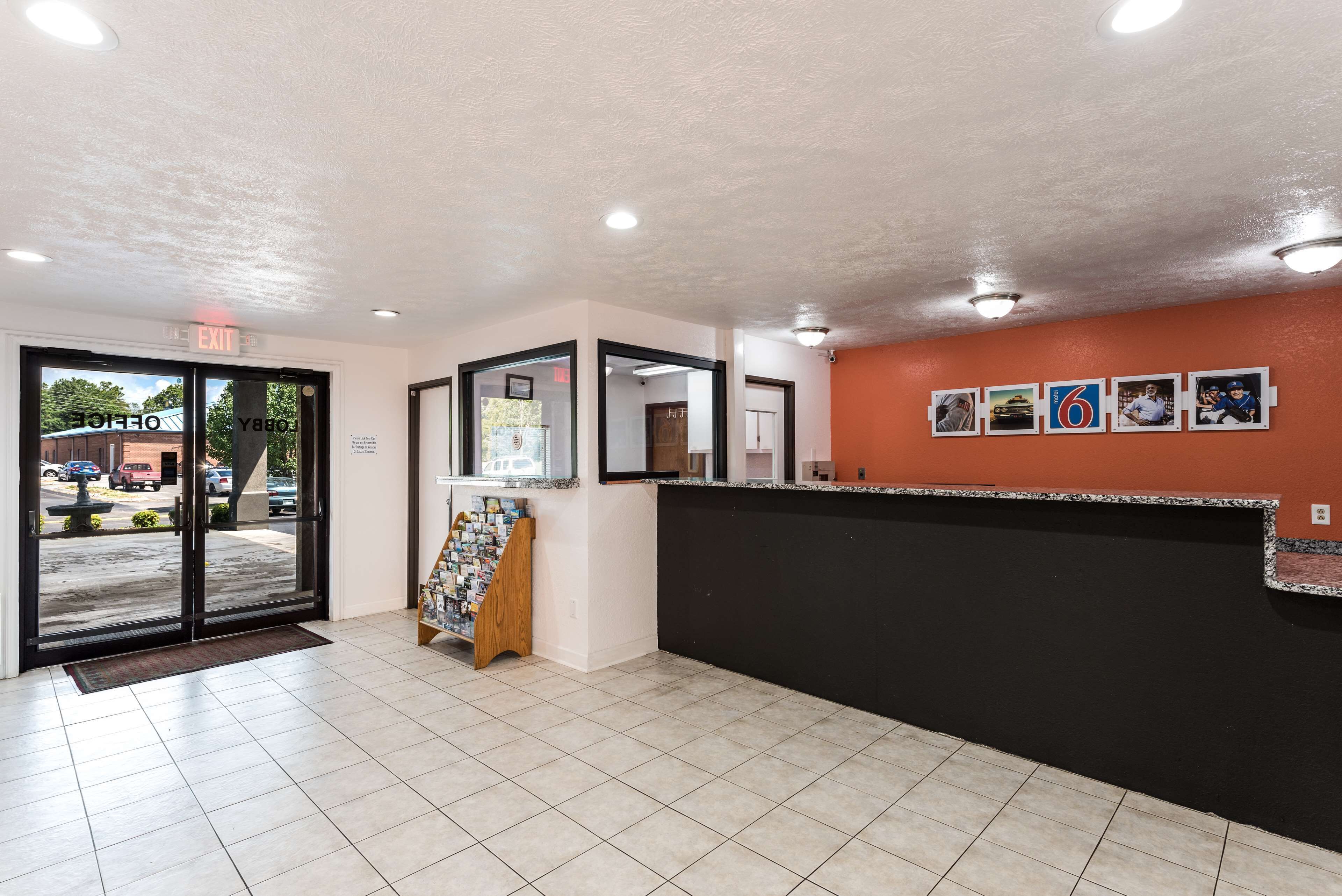 A reception area with a black counter, a glass door entrance, and a small display stand with brochures.