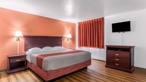 A hotel room with a bed, nightstands, a dresser, a TV, and a window with curtains. - Super Stay Plus (Morristown)