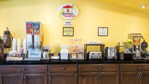Una barra de desayuno con un cartel que indica los horarios de atención, una máquina de café y diferentes alimentos.