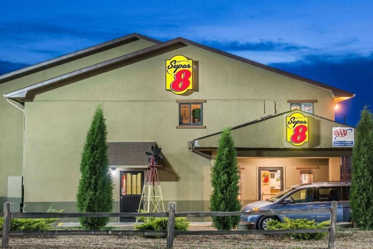Un motel Super 8 con un letrero llamativo, un automóvil estacionado al frente y un pequeño molino de viento.