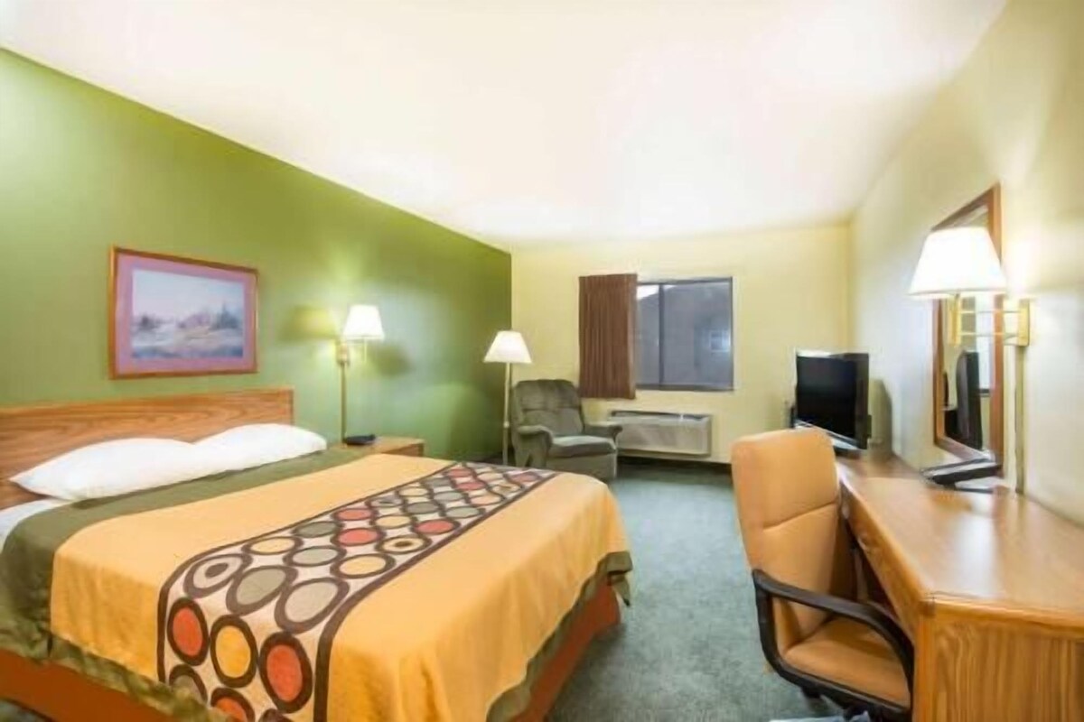 Une chambre d’hôtel avec un lit, un bureau, une chaise, une télévision et une fenêtre.