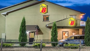 Un motel Super 8 con un letrero grande, un automóvil estacionado al frente y un molino de viento al fondo.