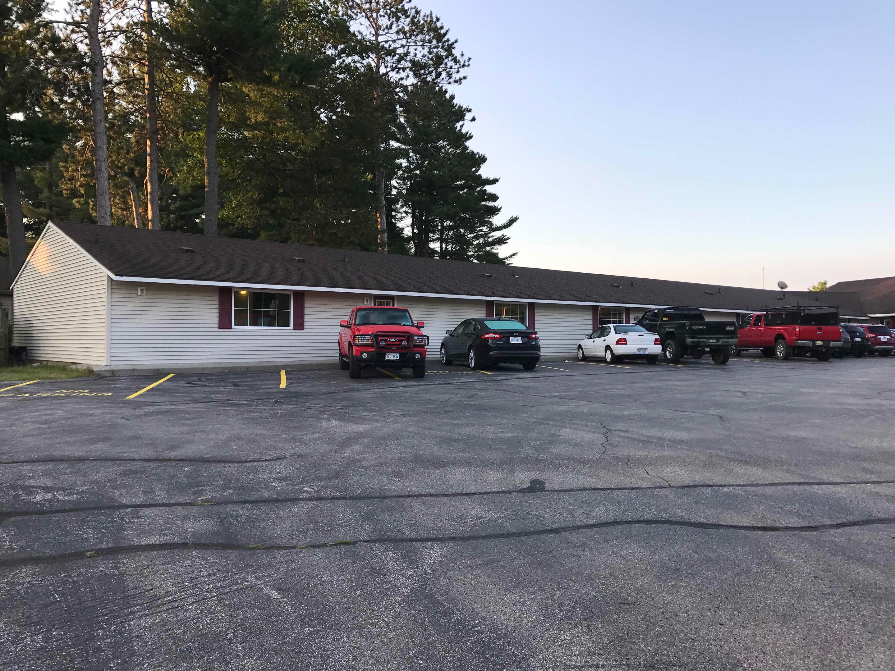 A motel with a row of parking spaces and a building with a sloped roof.