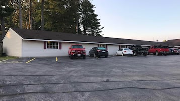 A motel with a row of parking spaces and a building with a sloped roof.