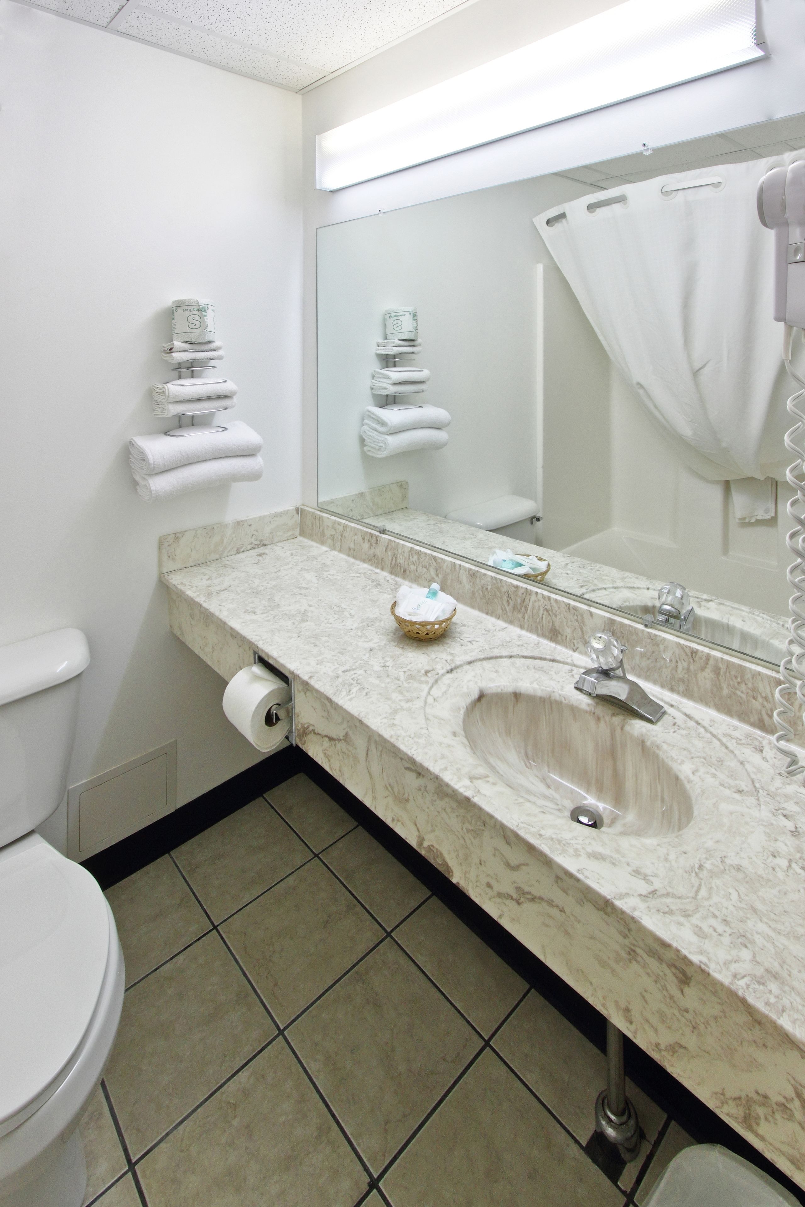 A bathroom with a marble sink, a large mirror, a toilet, and a shower curtain.