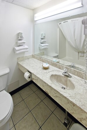 A bathroom with a marble sink, a large mirror, a toilet, and a shower curtain.