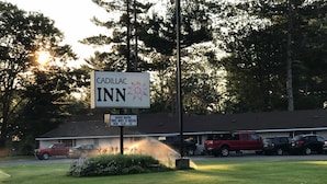 Une enseigne indiquant l’emplacement du Cadillac Inn, avec une pelouse et des voitures garées en arrière-plan.