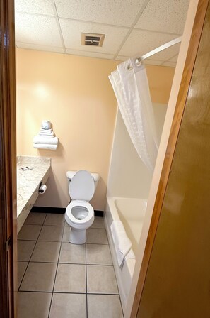 Un baño con inodoro, lavamanos y cortina de ducha.