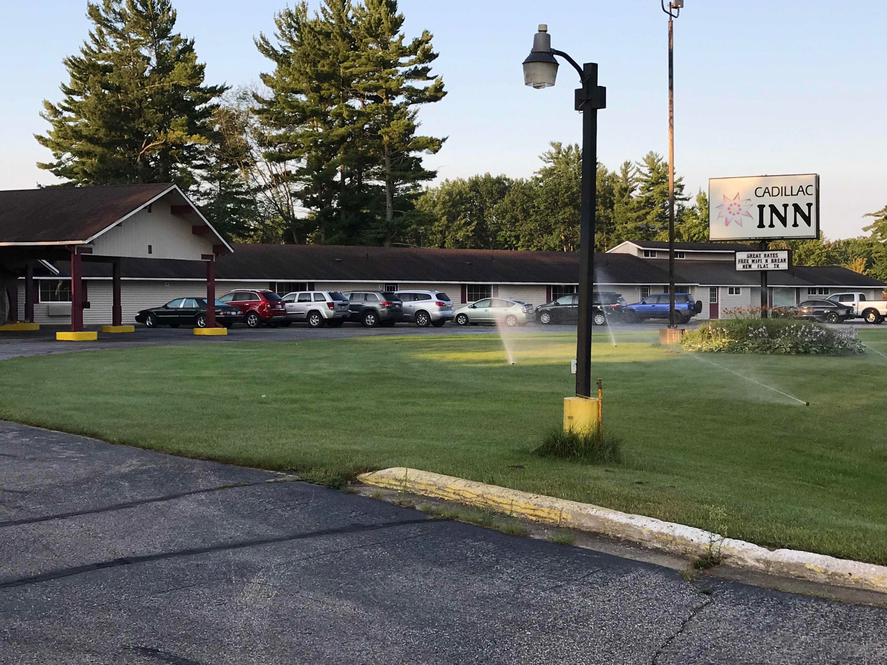 A Cadillac Inn with a parking lot, a covered waiting area, and a lawn in front.