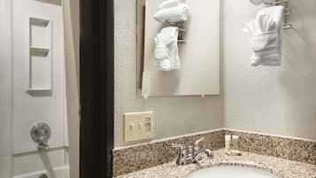 A bathroom with a granite countertop sink, a mirror, and towel racks on the wall.