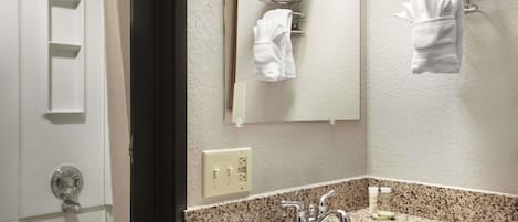 A bathroom with a granite countertop sink, a mirror, and towel racks on the wall.
