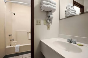 A bathroom with a bathtub, a sink with a mirror, and a towel rack with folded towels. - Super 8 by Wyndham Concordia (Concordia)