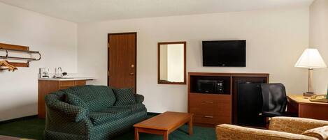 Una habitación de hotel con una cama, un sofá, un escritorio, un televisor y un microondas.