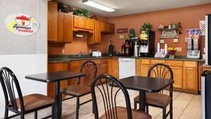 A small, clean kitchen with wooden cabinets, a coffee machine, and a sign indicating breakfast hours. - Super 8 by Wyndham Concordia (Concordia)