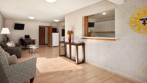 A modern living room with a sofa, a coffee table, and a TV. There is a kitchen area with cabinets and a countertop. - Super 8 by Wyndham Concordia (Concordia)
