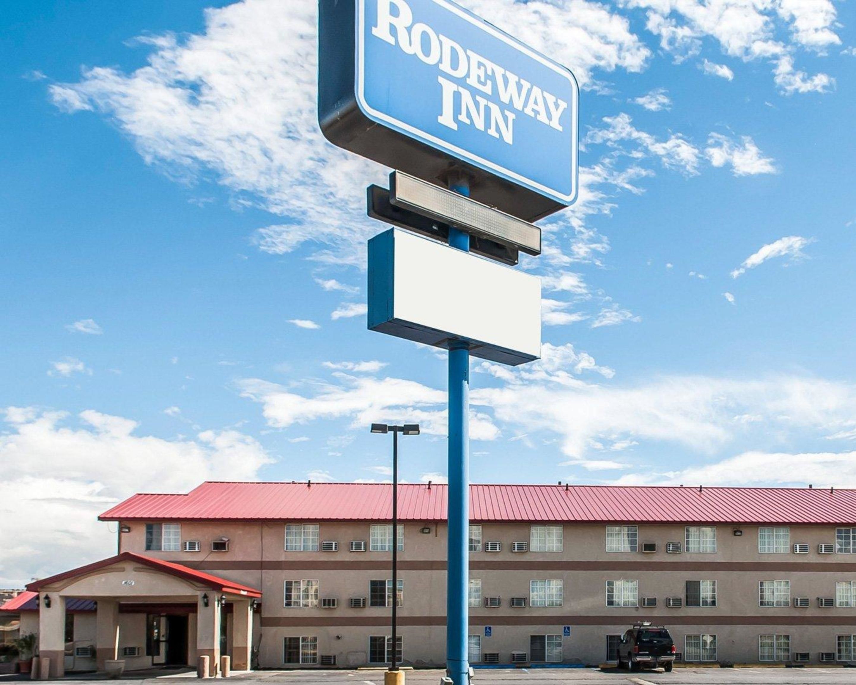 Un letrero de Rodeway Inn con un edificio al fondo.