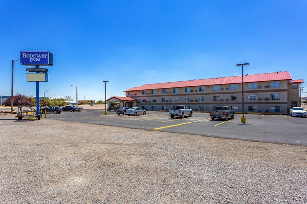 A parking lot with a Rodeway Inn sign, multiple cars, and a building with a red roof.