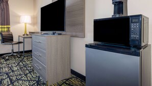 A hotel room with a flat-screen TV, a coffee maker, a desk with a lamp, and a chair. - Super 8 by Wyndham Pratt (Pratt)