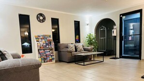 A living room with a sofa, coffee table, and a bookshelf filled with magazines. - Super 8 by Wyndham Pratt (Pratt)