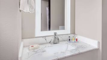 A bathroom with a white marble sink, a modern faucet, and a mirror above it.