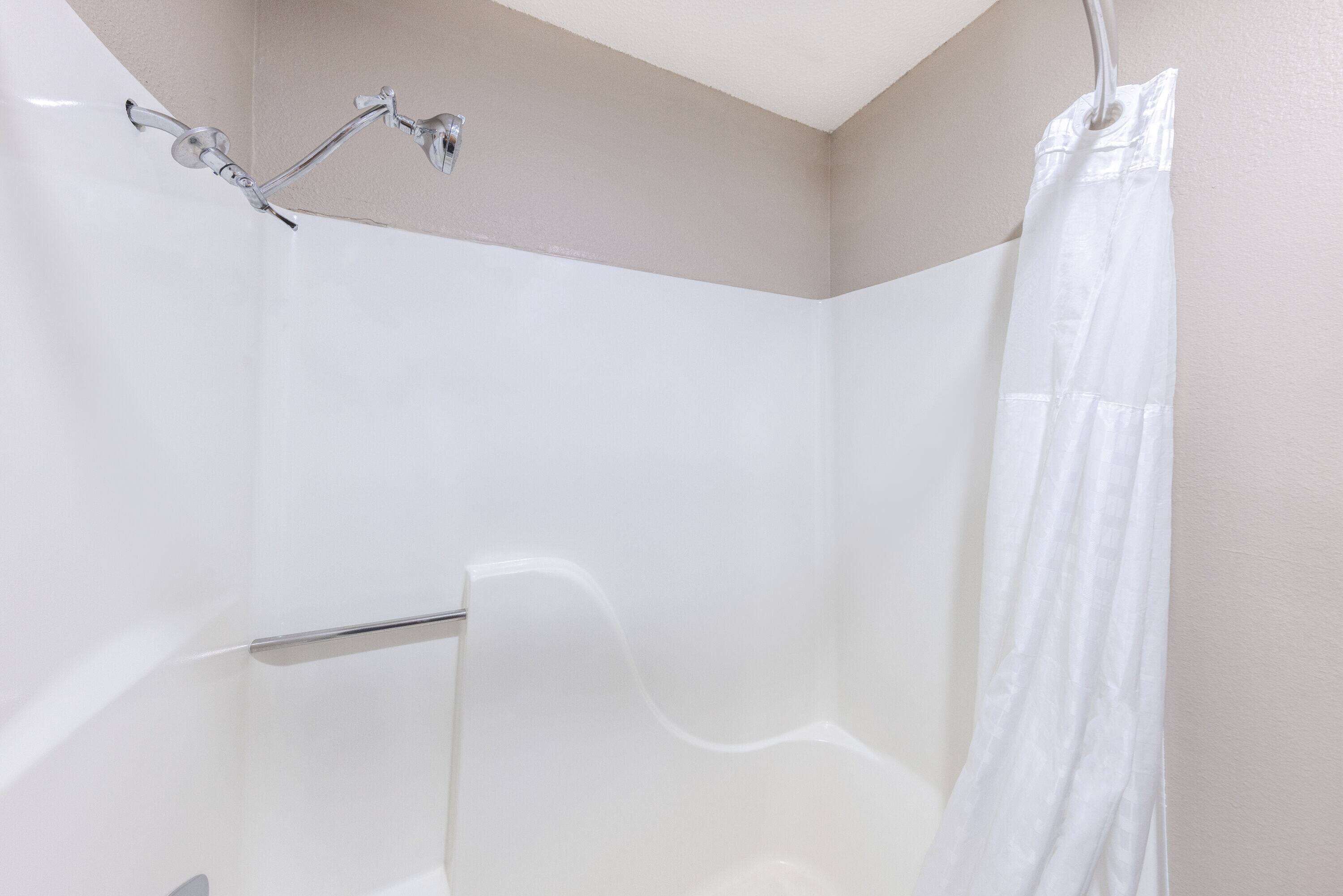 A shower with a white curtain and chrome fixtures.