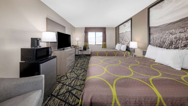 A hotel room with a large bed, a desk with a computer, a TV, and a microwave. - Super 8 by Wyndham Pratt (Pratt)