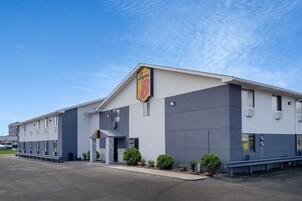 Un hotel Super 8 con un diseño moderno, con techo plano, ventanas amplias y estacionamiento.