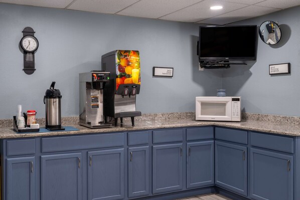 A kitchen with a coffee machine, microwave, and a clock on the wall.