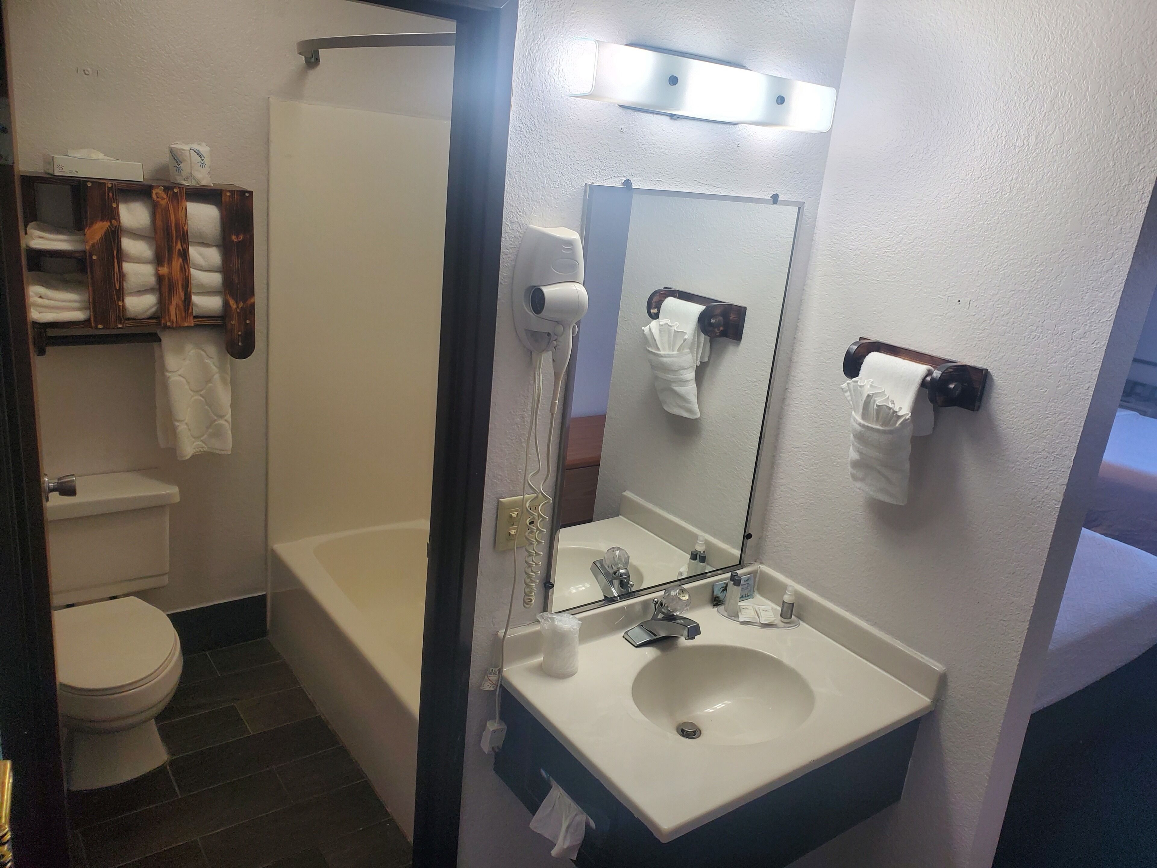 A bathroom with a toilet, a sink, a mirror, and a shower.