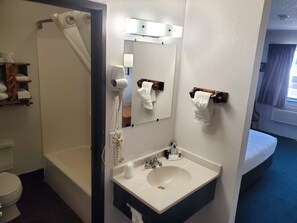 A bathroom with a bathtub, a sink, a mirror, and a toilet. - Glendive Lodge (Glendive)