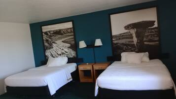 Una habitación de hotel con dos camas individuales, una mesita de noche con una lámpara y dos lámparas de pared.