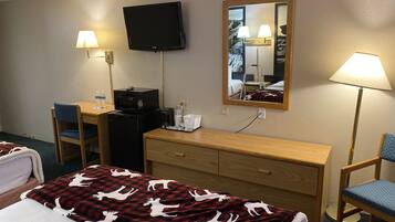 A hotel room with a bed, a desk, a chair, a television, a mirror, and a lamp.