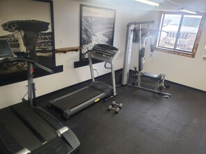 A gym with a treadmill, weight bench, and dumbbells. - Glendive Lodge (Glendive)