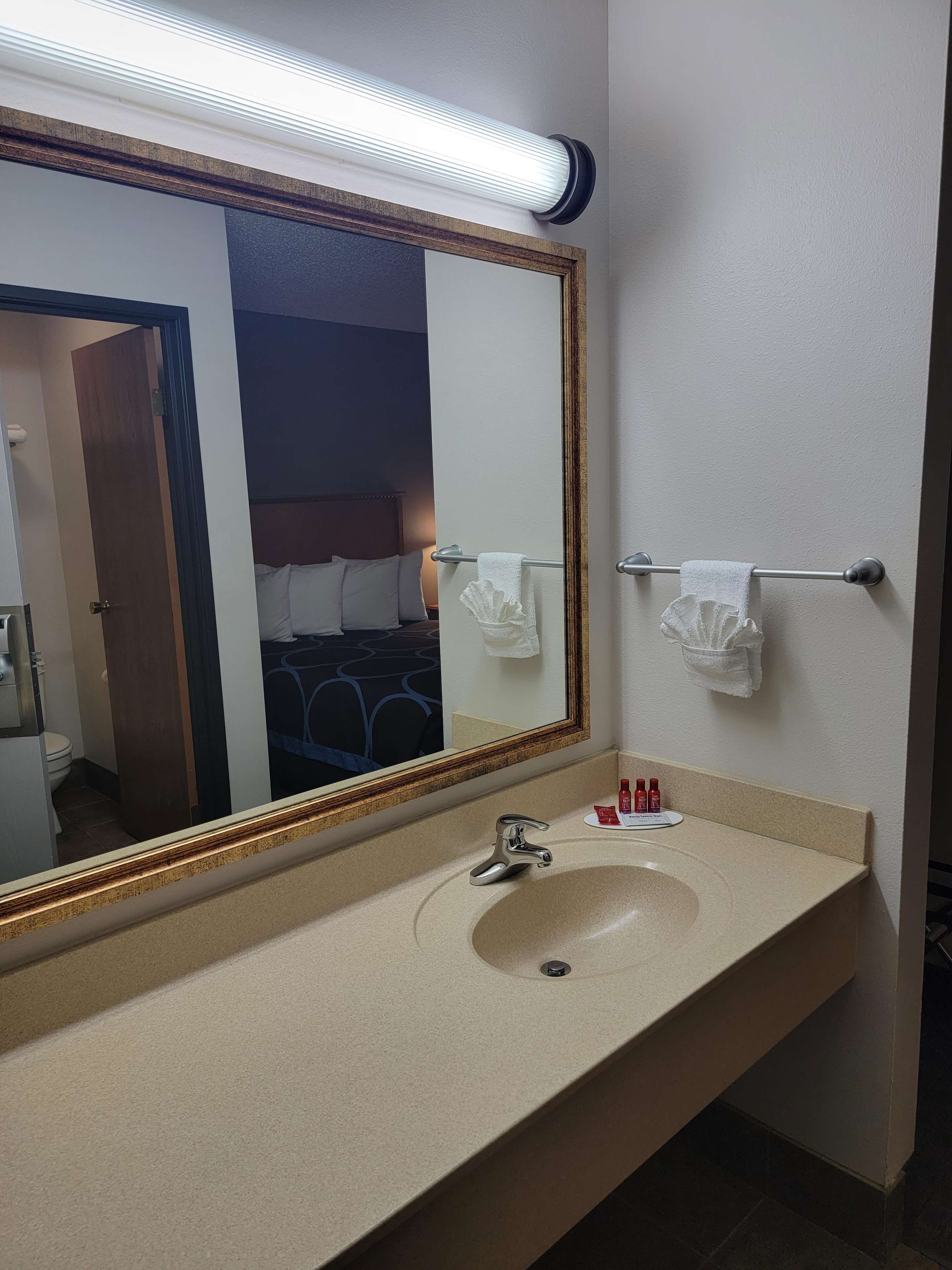 A hotel bathroom with a large mirror, a sink, and a towel rack.