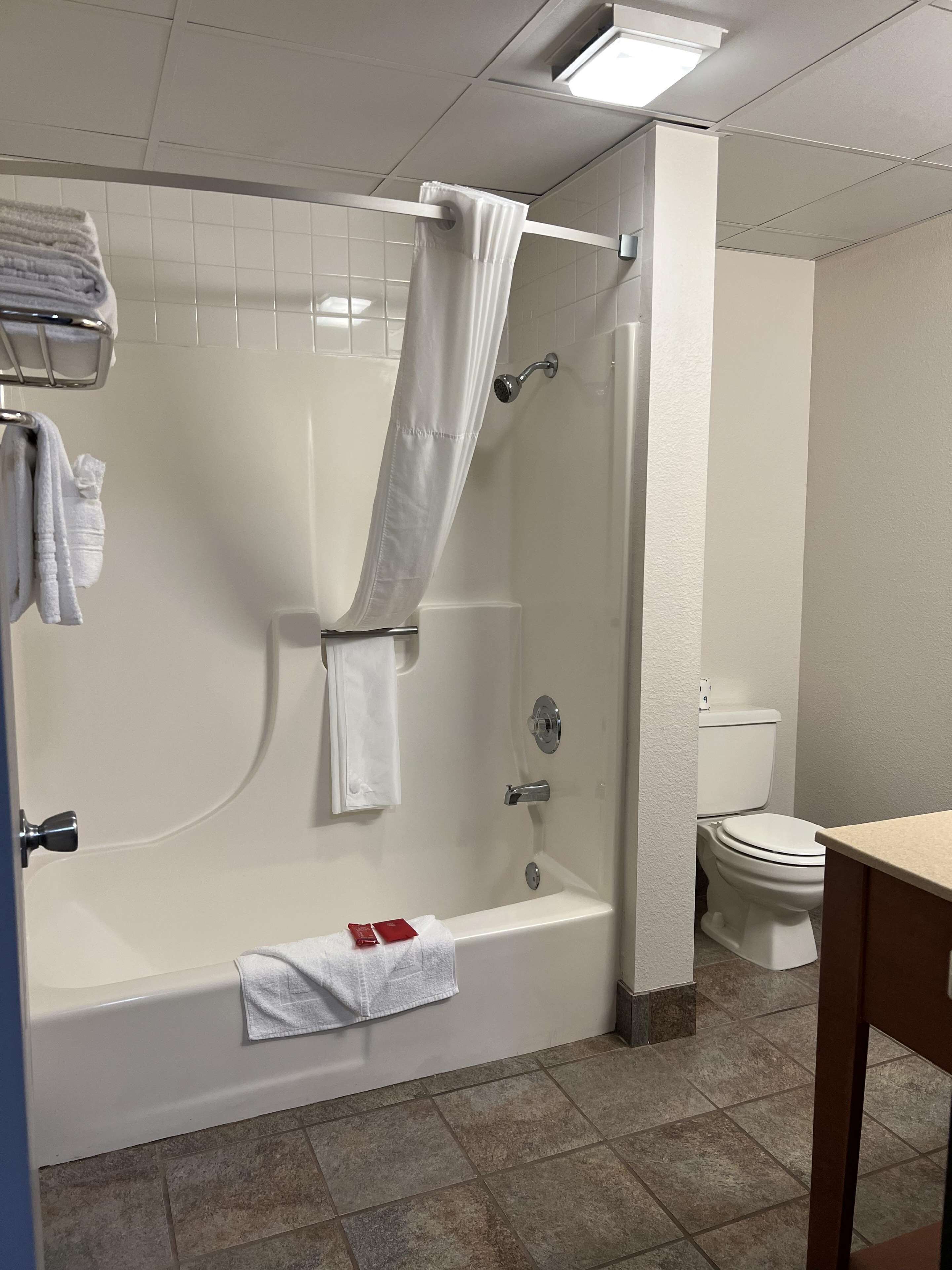 A bathroom with a bathtub, shower, toilet, and a towel rack with towels.