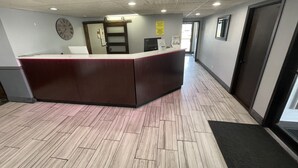 A reception area with a marble-patterned floor, a reception desk, a clock, and a door. - Super 8 by Wyndham Beaver Dam (Beaver Dam)