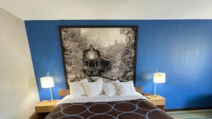 A hotel room with a large bed, two bedside tables, and a headboard with a black and white photograph. - Super 8 by Wyndham Beaver Dam (Beaver Dam)