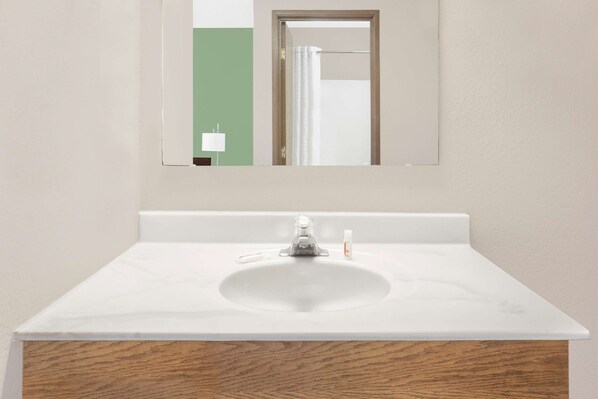 Un baño con un lavabo blanco, un espejo y una pared verde.