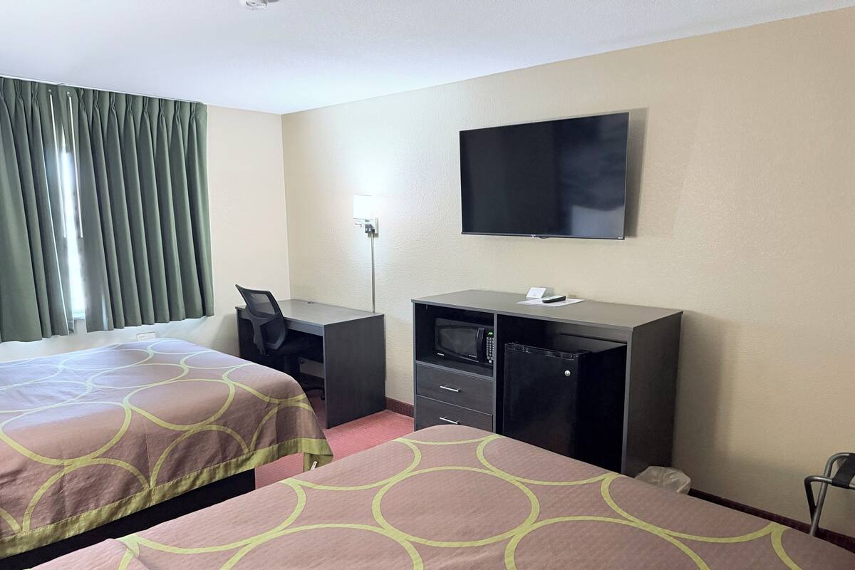 Een hotelkamer met twee bedden, een bureau, een televisie, een magnetron en een koelkast.