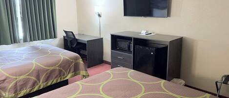 Habitación de hotel con dos camas, un escritorio, un televisor, un microondas y un refrigerador.