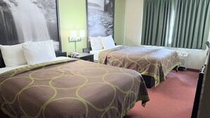 Une chambre d’hôtel avec deux lits, un grand téléviseur fixé au mur, un bureau avec un téléphone et une fenêtre avec des rideaux.