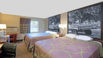 A hotel room with two beds, a desk with a chair, a window with curtains, an air conditioning unit, and a large framed picture on the wall.