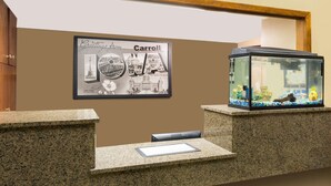 A reception desk with a framed welcome sign, a fish tank, and a small seating area. - Super 8 by Wyndham Carroll (Carroll)