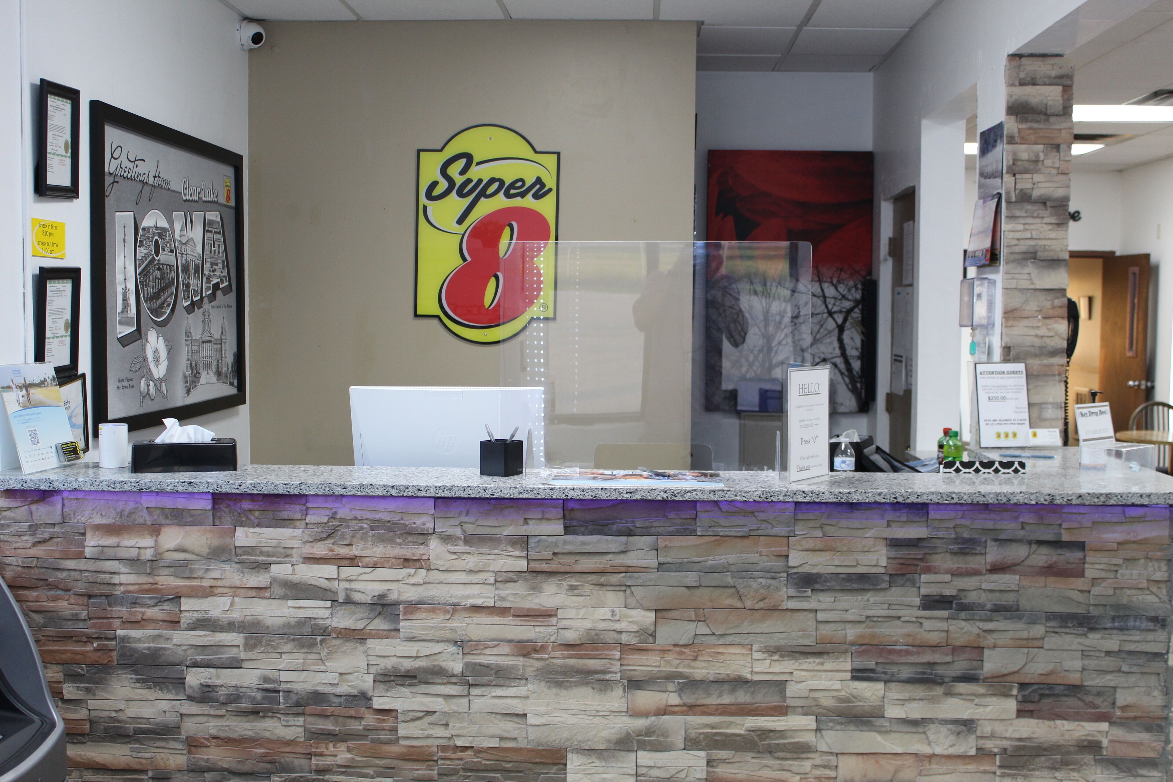 Un mostrador de recepción con una pared de piedra, obras de arte enmarcadas y un letrero de 'Super 8'.
